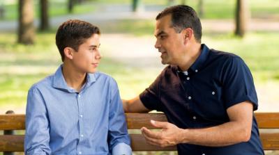 Father and son talking on park bench